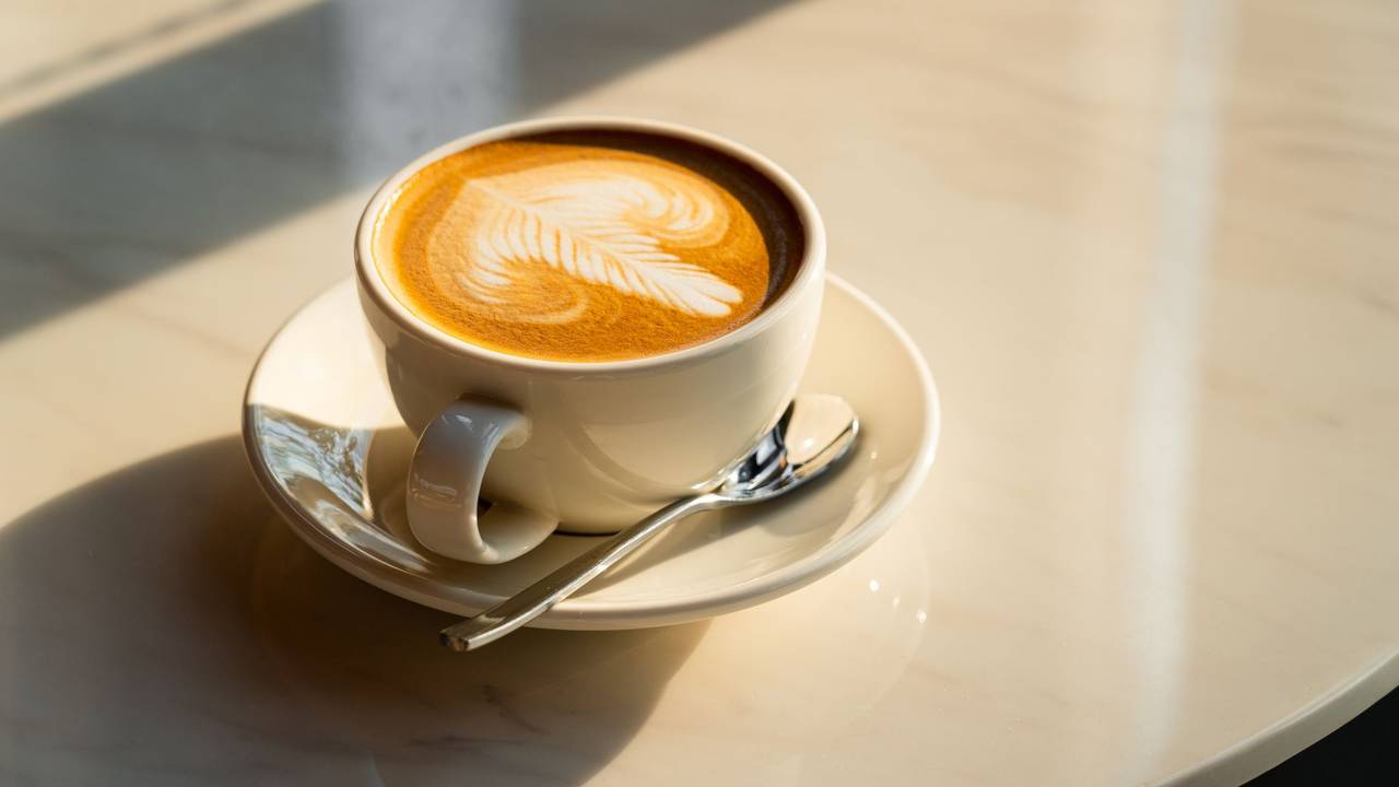 Auf dem Foto sieht man eine Tasse Kaffee auf einem Tisch stehen.