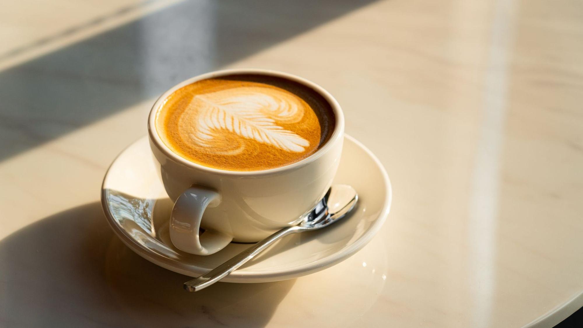 Auf dem Foto sieht man eine Tasse Kaffee auf einem Tisch stehen.
