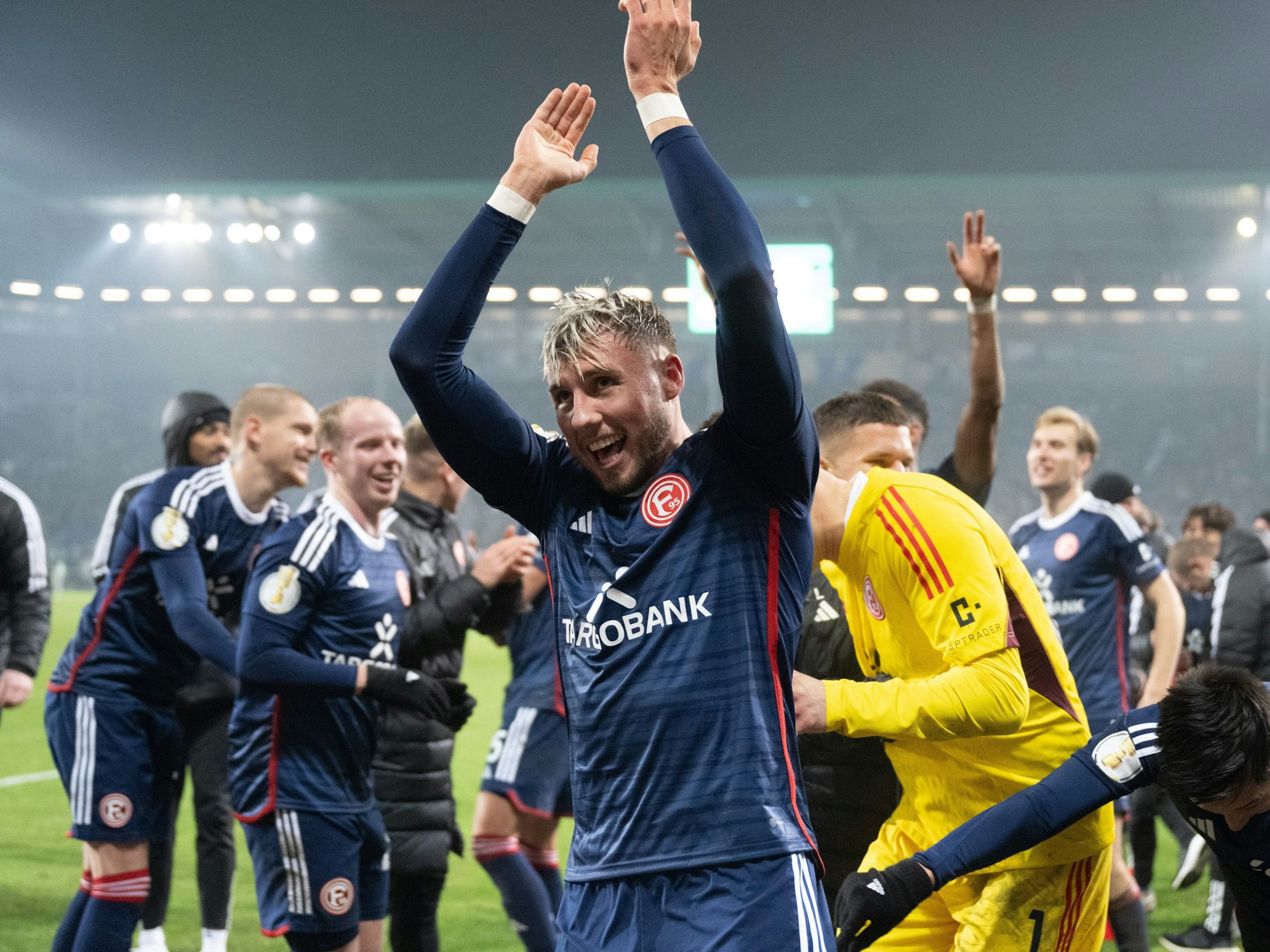 Jona Niemiec jubelt mit der Mannschaft von Fortuna Düsseldorf vor der Fankurve nach dem Pokalspiel beim 1. FC Magdeburg.