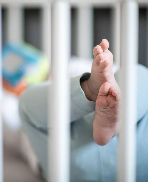 Die Füße eines Babys sind in einem Kinderbett zu sehen.