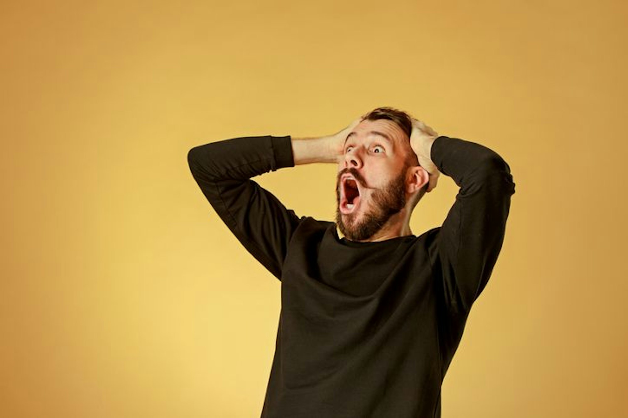 Portrait of young man with shocked facial expression over orange studio background