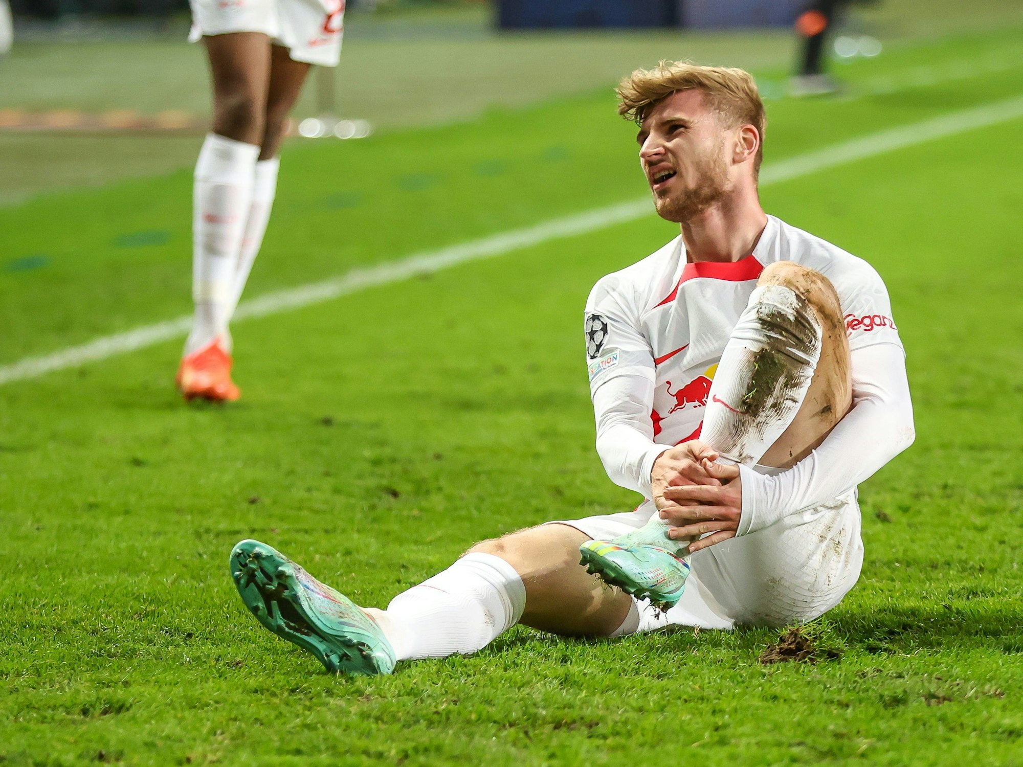 Timo Werner sitzt auf dem Rasen und hält sich das Bein.
