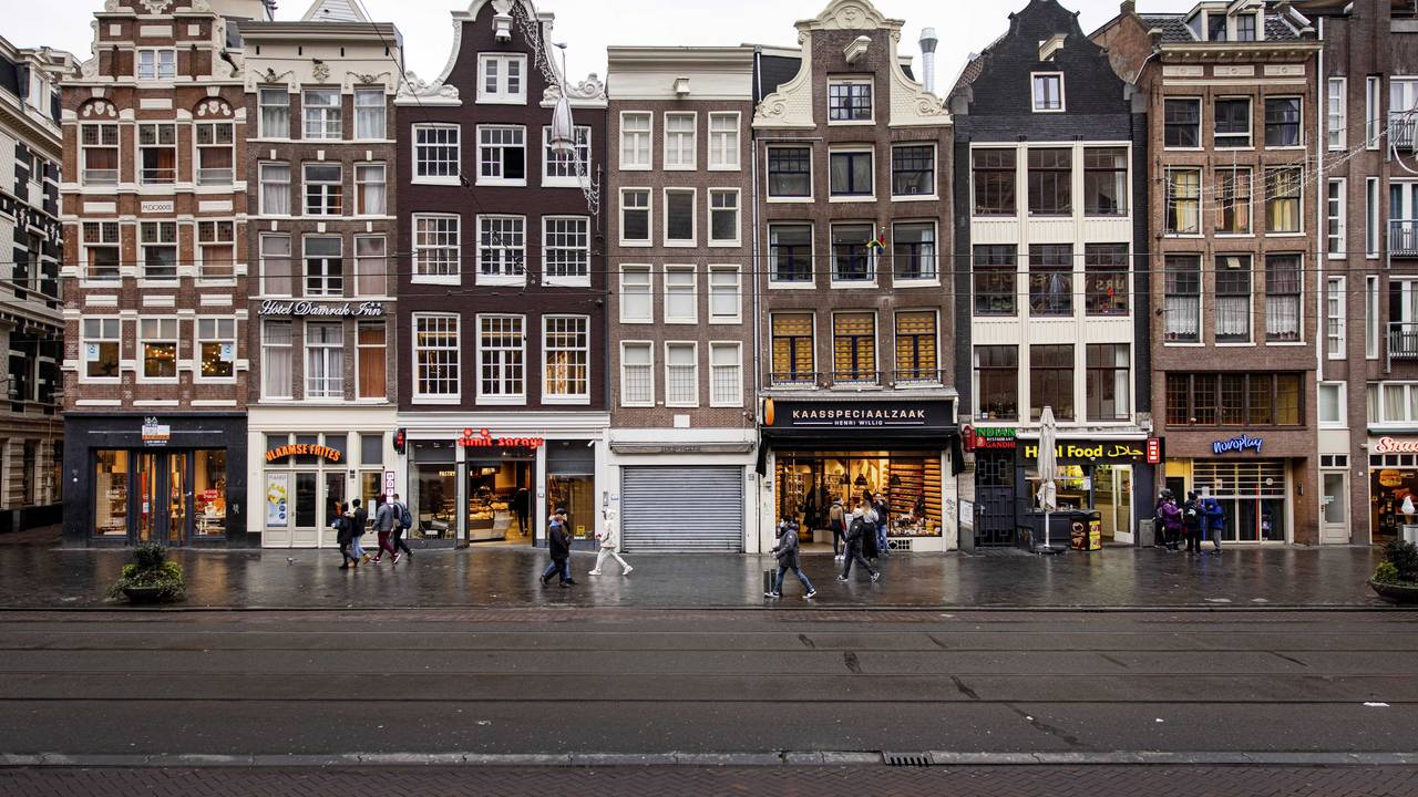 Einige Personen gehen an Geschäften im Stadtzentrum von Amsterdam vorbei.