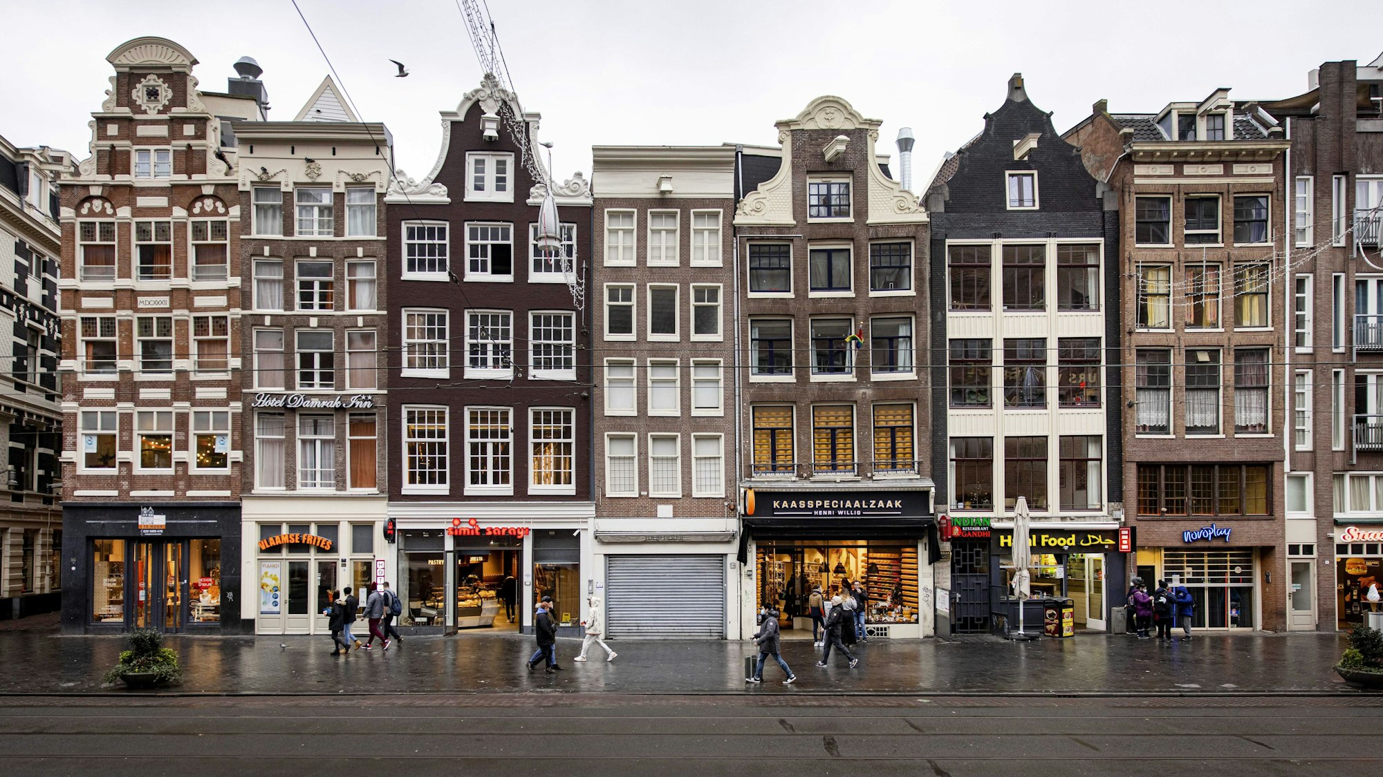 Einige Personen gehen an Geschäften im Stadtzentrum von Amsterdam vorbei.