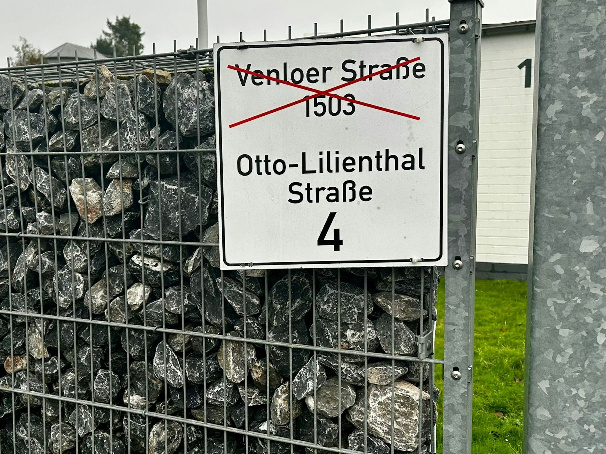 Ein Schild mit der durchgestrichenen Adresse Venloer Straße 1503 und der richtigen Adresse Otto-Lilienthal-Straße 4 ist zu sehen.