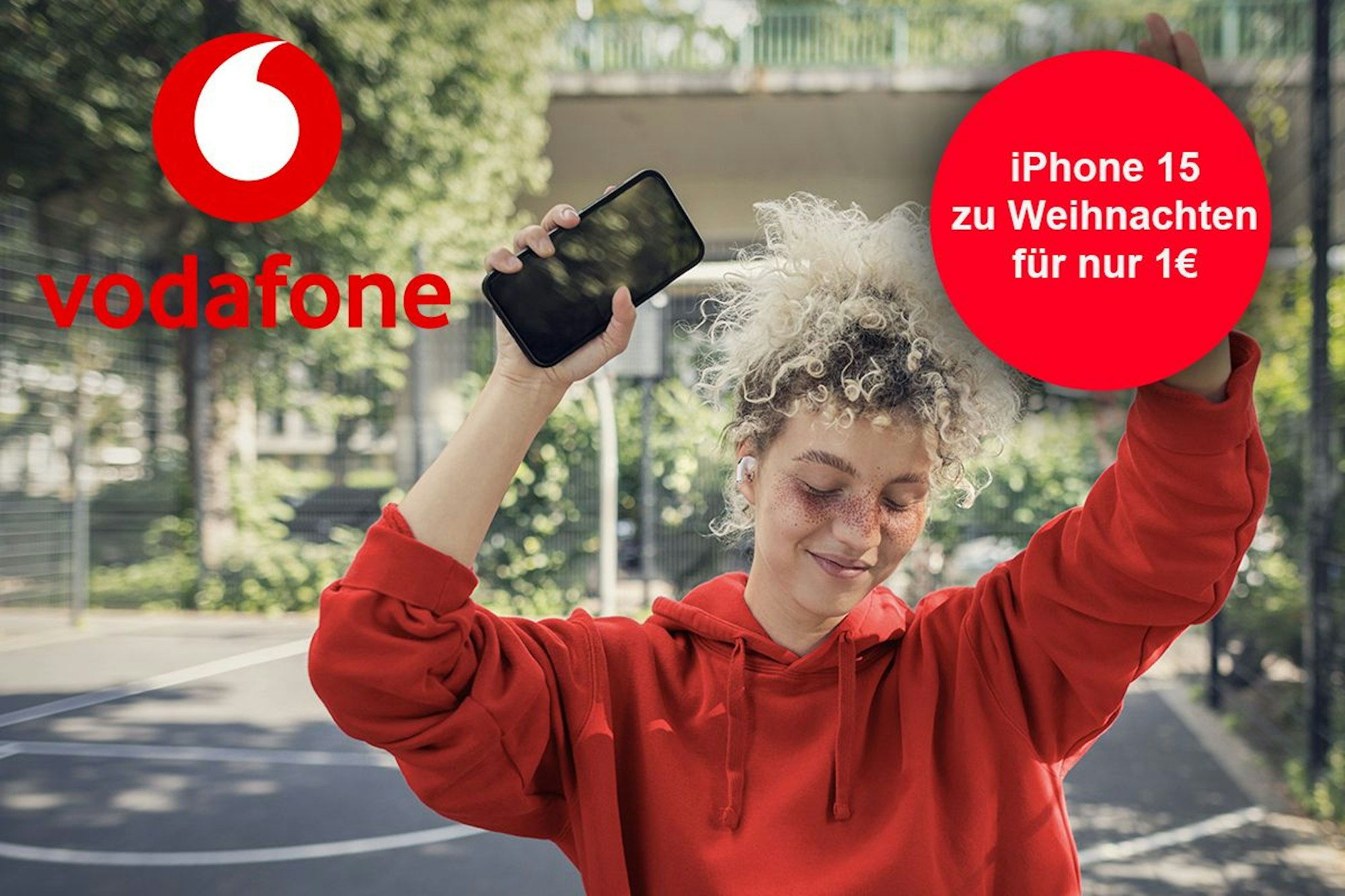 Junge Frau hält iPhone in der Hand und lächelt. Vodafone Logo im Bild.