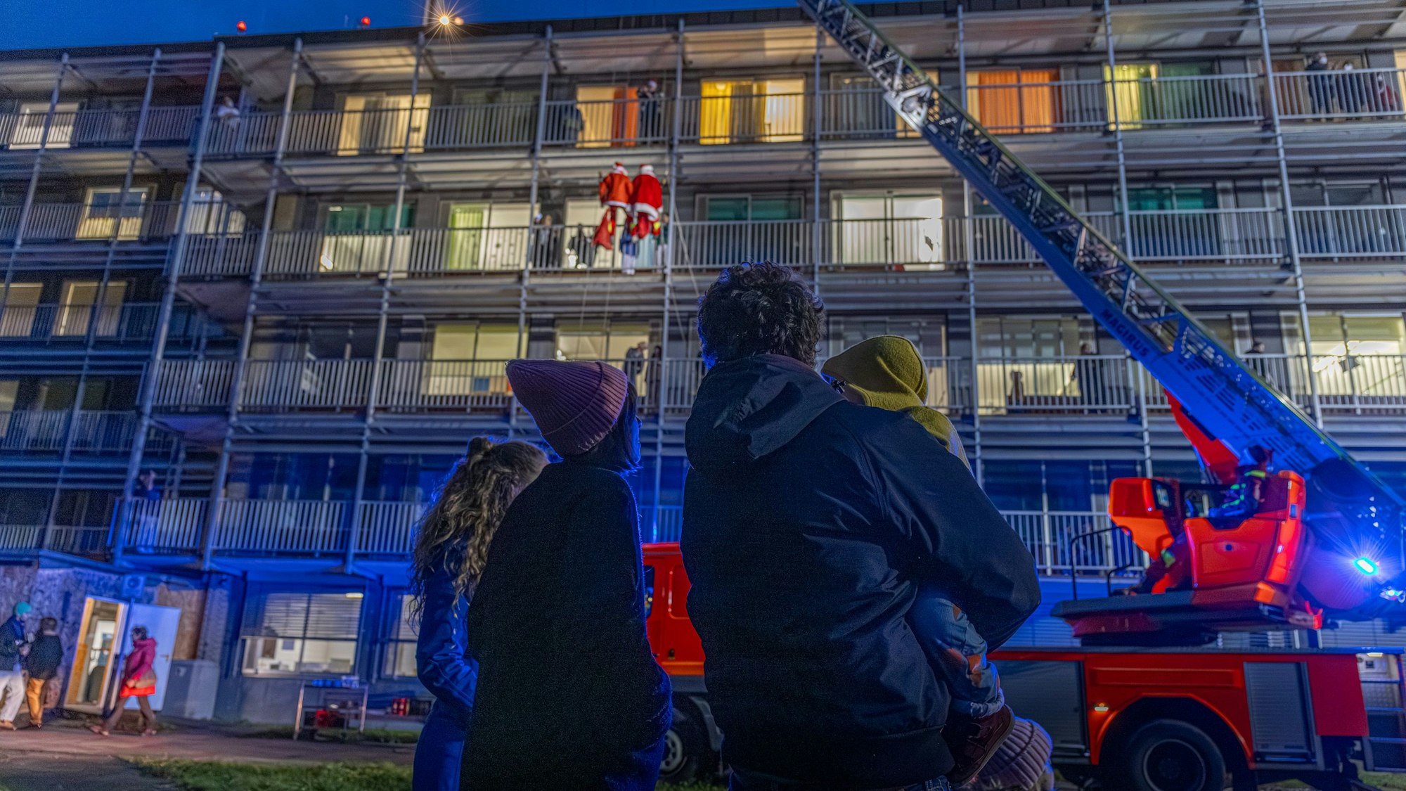 Menschen schauen von unten auf einen Einsatz der Feuerwehr an einem Krankenhaus.