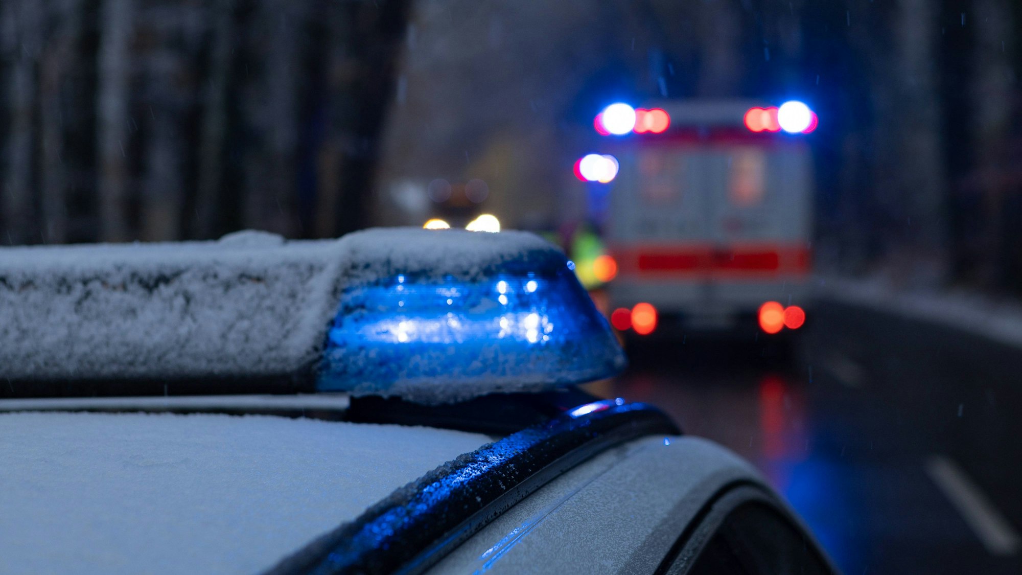 Polizei und Rettungswagen stehen mit Blaulicht auf der Straße.
