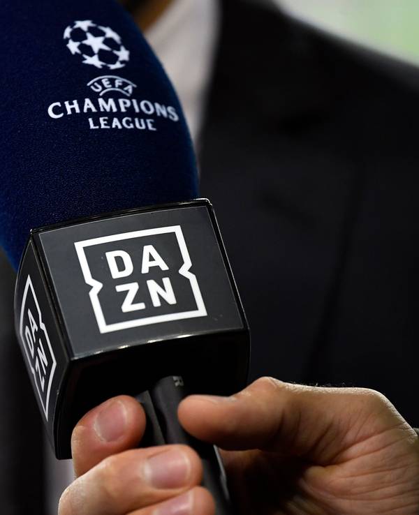 Ein Reporter hält ein Mikrofon des Streamingdienstes DAZN während eines Interviews fest.