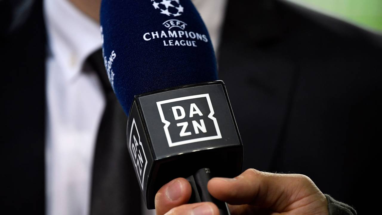 Ein Reporter hält ein Mikrofon des Streamingdienstes DAZN während eines Interviews fest.