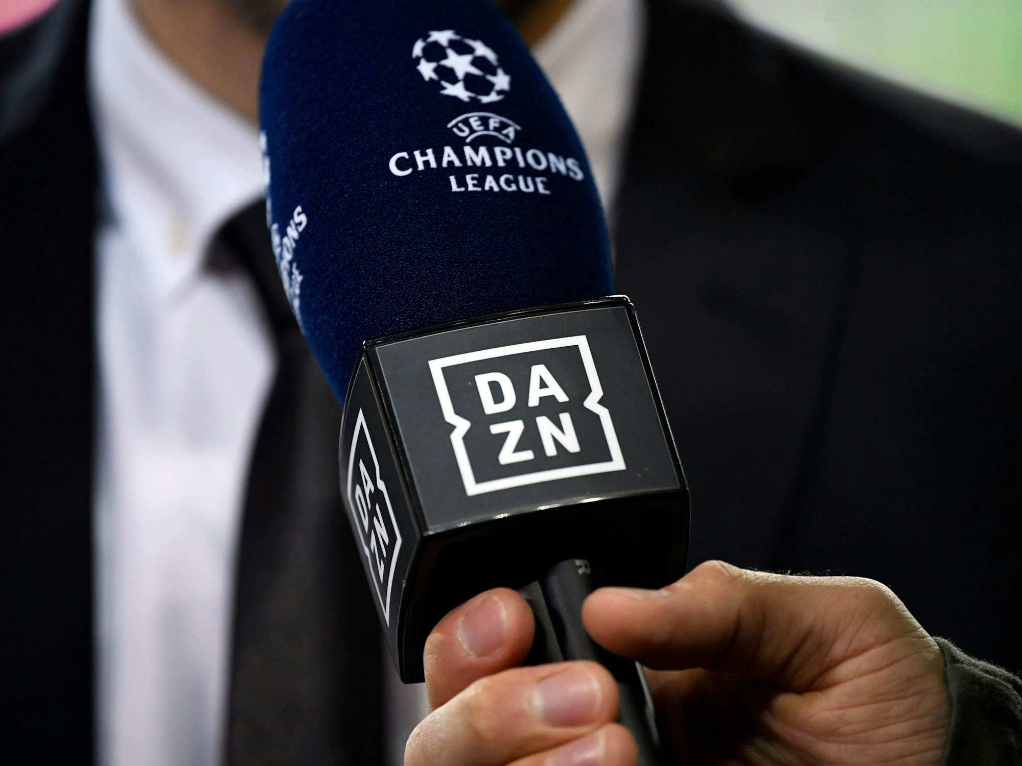 Ein Reporter hält ein Mikrofon des Streamingdienstes DAZN während eines Interviews fest.
