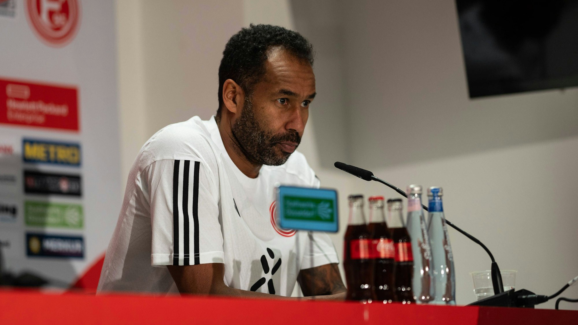 Fortuna Düsseldorfs Cheftrainer Daniel Thioune sitzt bei der Pressekonferenz auf dem Podium.