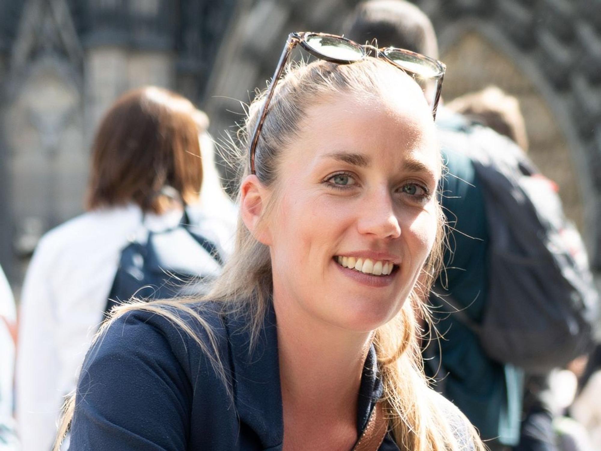 Ruth Wolfram sitzt vorm Kölner Dom und lächelt.