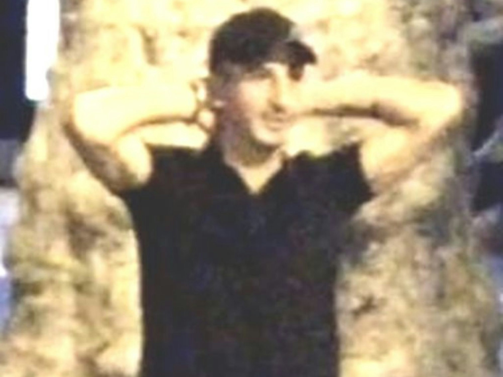 Ein junger Mann trägt ein Basecap und hält beide Hände hinter den Kopf.