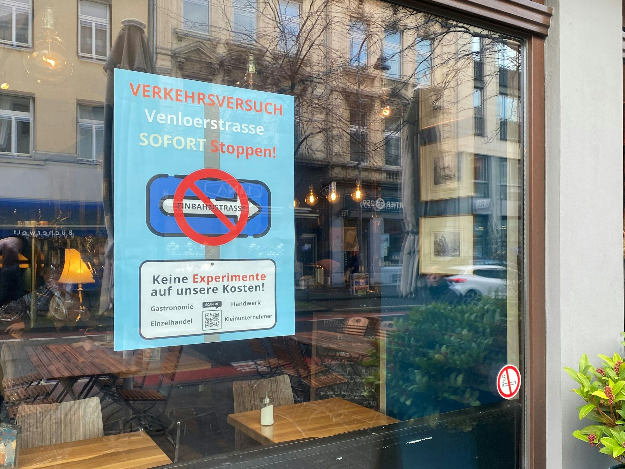 Ein Plakat mit der Aufforderung den Verkehrsversuch zu beenden hängt in einem Schaufenster.