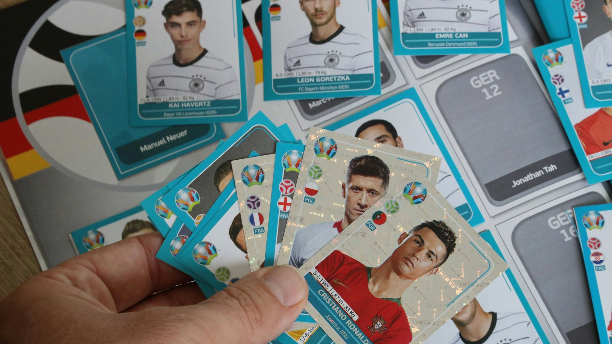 Ein Mann hält mehrere Sammel-Sticker von Panini für die EM 2021 in der Hand. Bei der EM 2024 übernimmt Konkurrent Topps die Rechte.