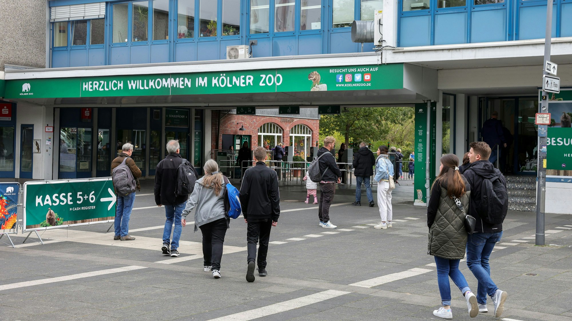Blick auf den Haupteingang des Kölner Zoos, einige Menschen gehen rein und raus.