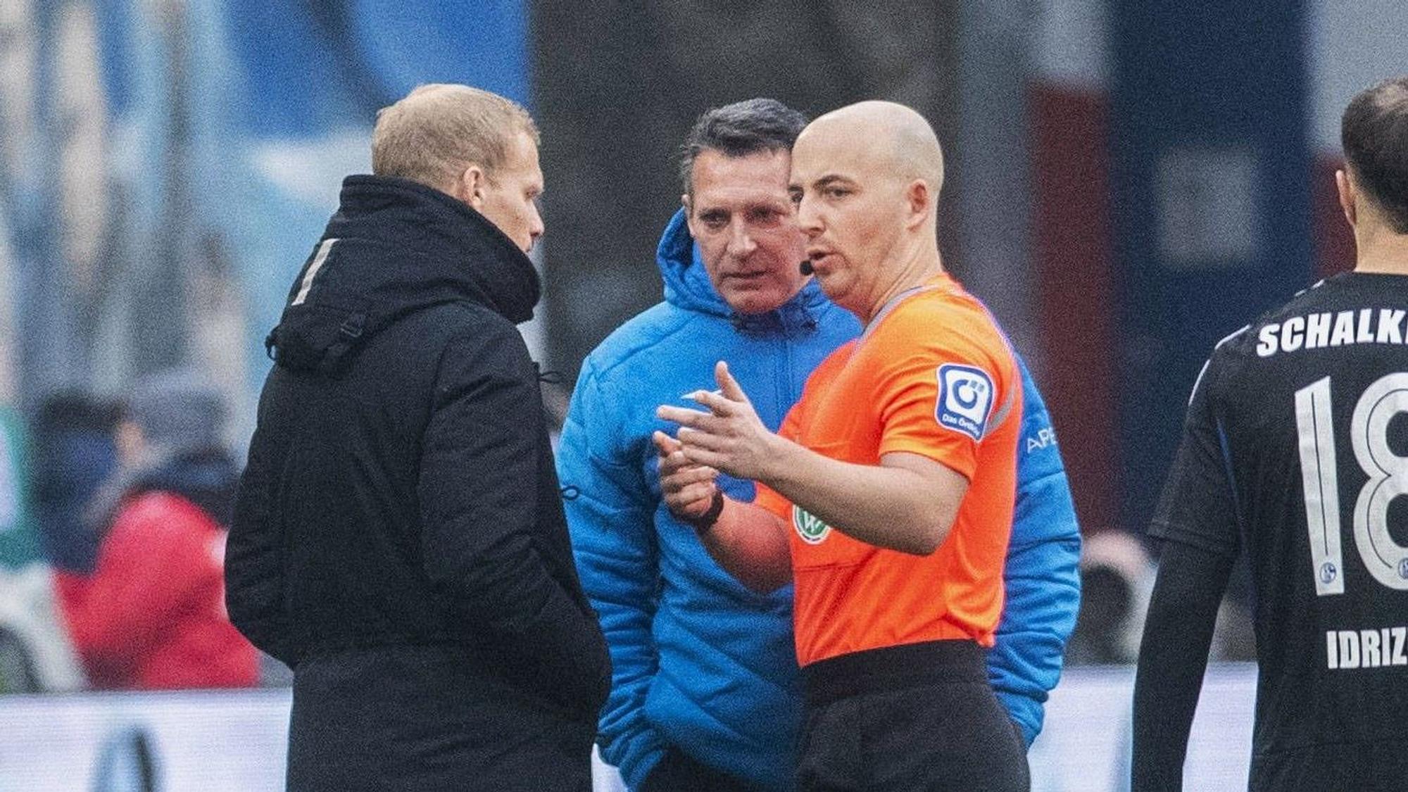 Rostock-Trainer Alois Schwartz (M.) spricht nach dem Spiel gegen Schalke 04 mit S04-Coach Karel Geraerts und Schiedsrichter Nicolas Winter.