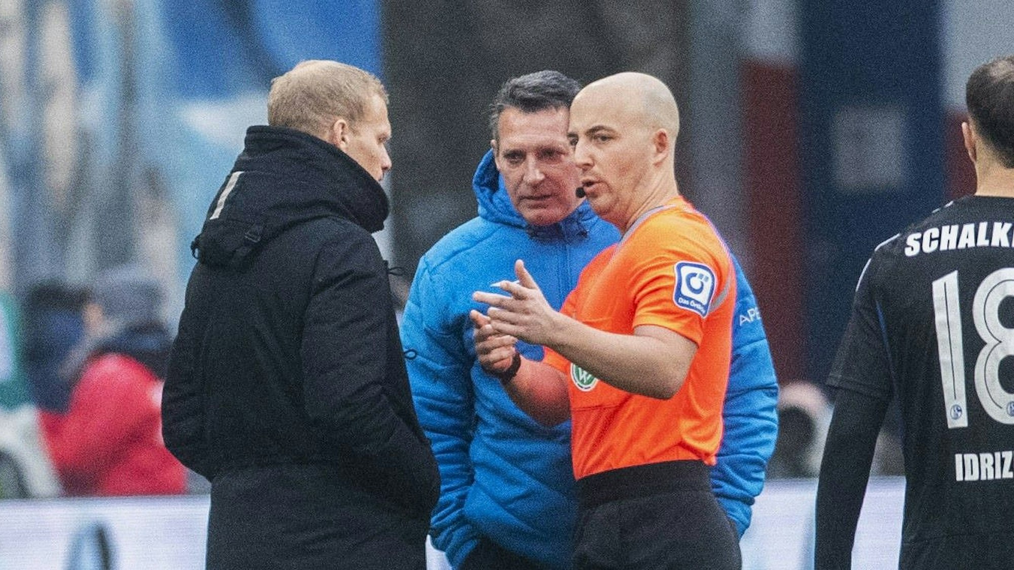 Rostock-Trainer Alois Schwartz (M.) spricht nach dem Spiel gegen Schalke 04 mit S04-Coach Karel Geraerts und Schiedsrichter Nicolas Winter.