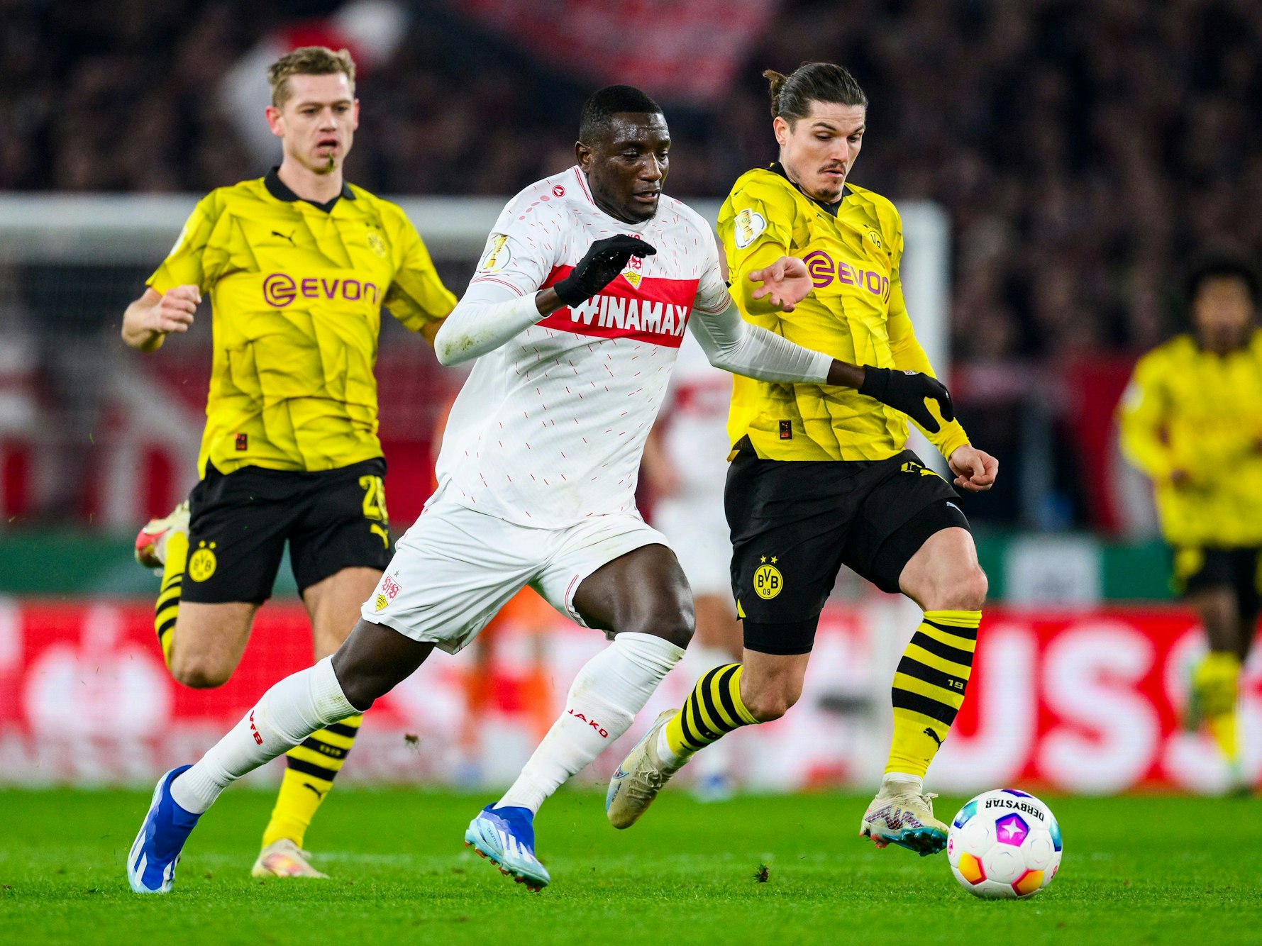Stuttgarts Serhou Guirassy (M) in Aktion gegen Dortmunds Julian Ryerson (l) und Dortmunds Marcel Sabitzer (r).