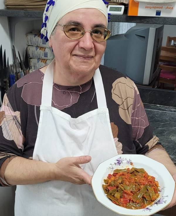 Eine Frau steht in einer Küche und hält einen Teller mit Essen in den Händen.