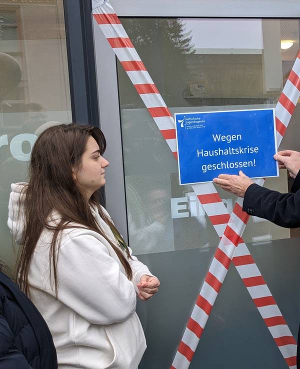 Georg Spitzley bringt ein Schild an, auf dem „Wegen Haushaltskrise geschlossen!“ steht.