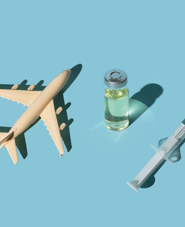 Vials, syringes with a vaccine and airplane on a blue background. Concept COVID-19 vaccine immunization and travel to the pandemic.