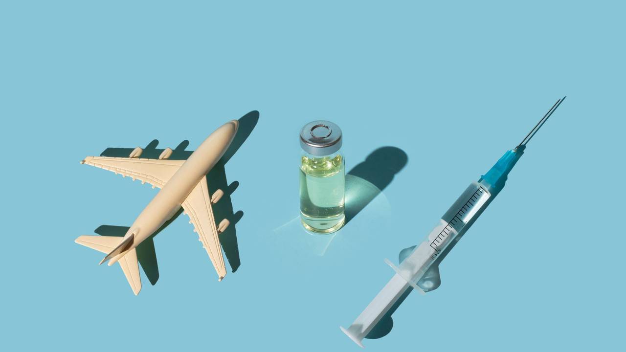 Vials, syringes with a vaccine and airplane on a blue background. Concept COVID-19 vaccine immunization and travel to the pandemic.