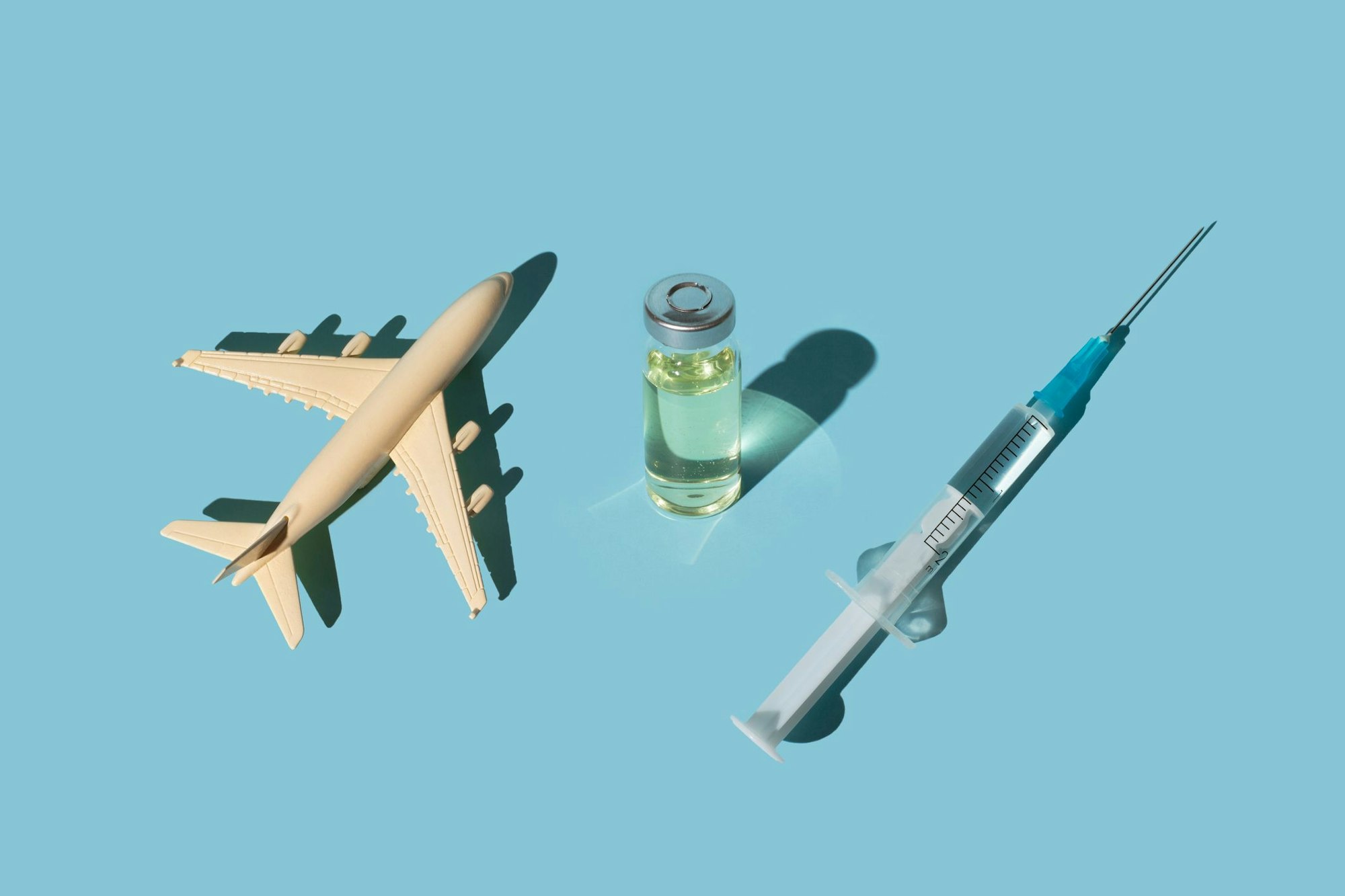 Vials, syringes with a vaccine and airplane on a blue background. Concept COVID-19 vaccine immunization and travel to the pandemic.