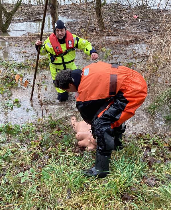 Ein Feuerwehrmann zieht eine nackte weibliche Puppe an Land.