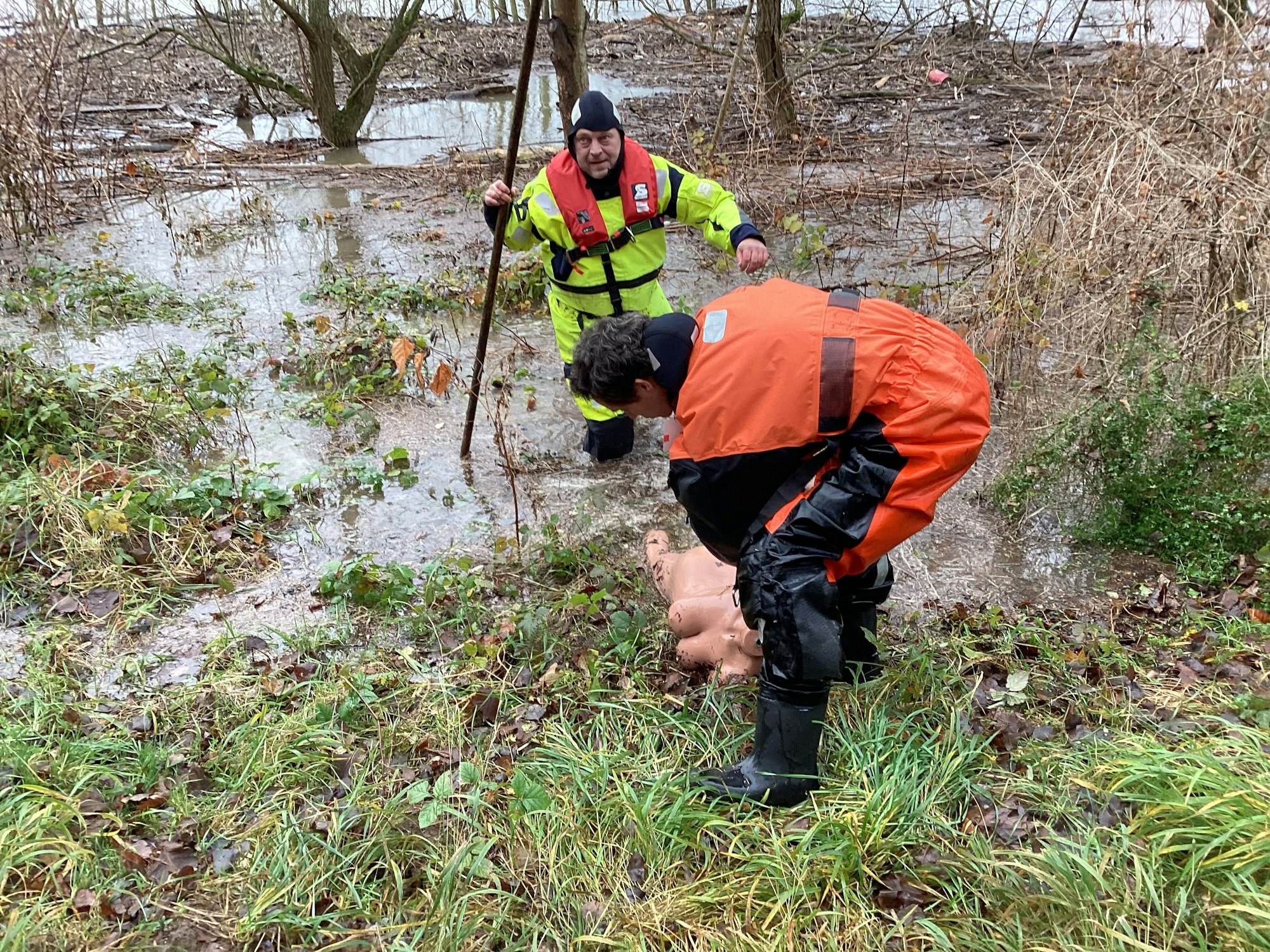 Ein Feuerwehrmann zieht eine nackte weibliche Puppe an Land.