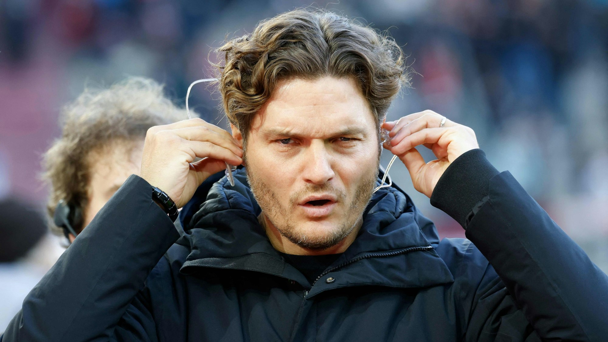 Edin Terzic steckt sich vor einem TV-Interview Kopfhörer in die Ohren.