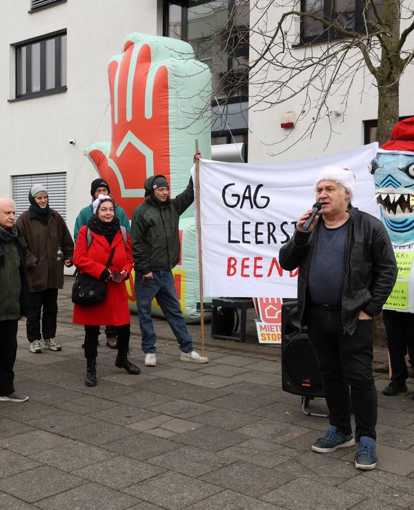 Eine Gruppe von Menschen steht bei einer Demo vor einem Gebäude.