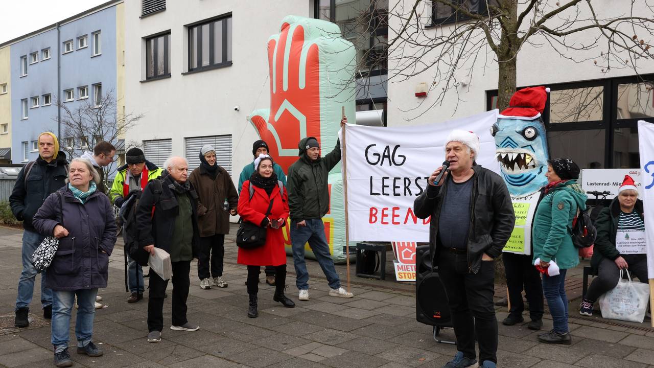 Eine Gruppe von Menschen steht bei einer Demo vor einem Gebäude.