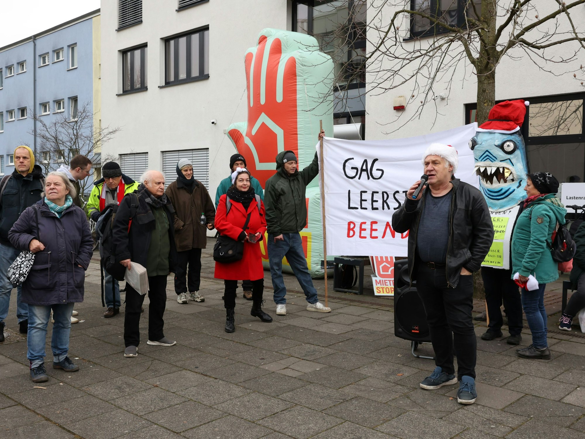 Eine Gruppe von Menschen steht bei einer Demo vor einem Gebäude.