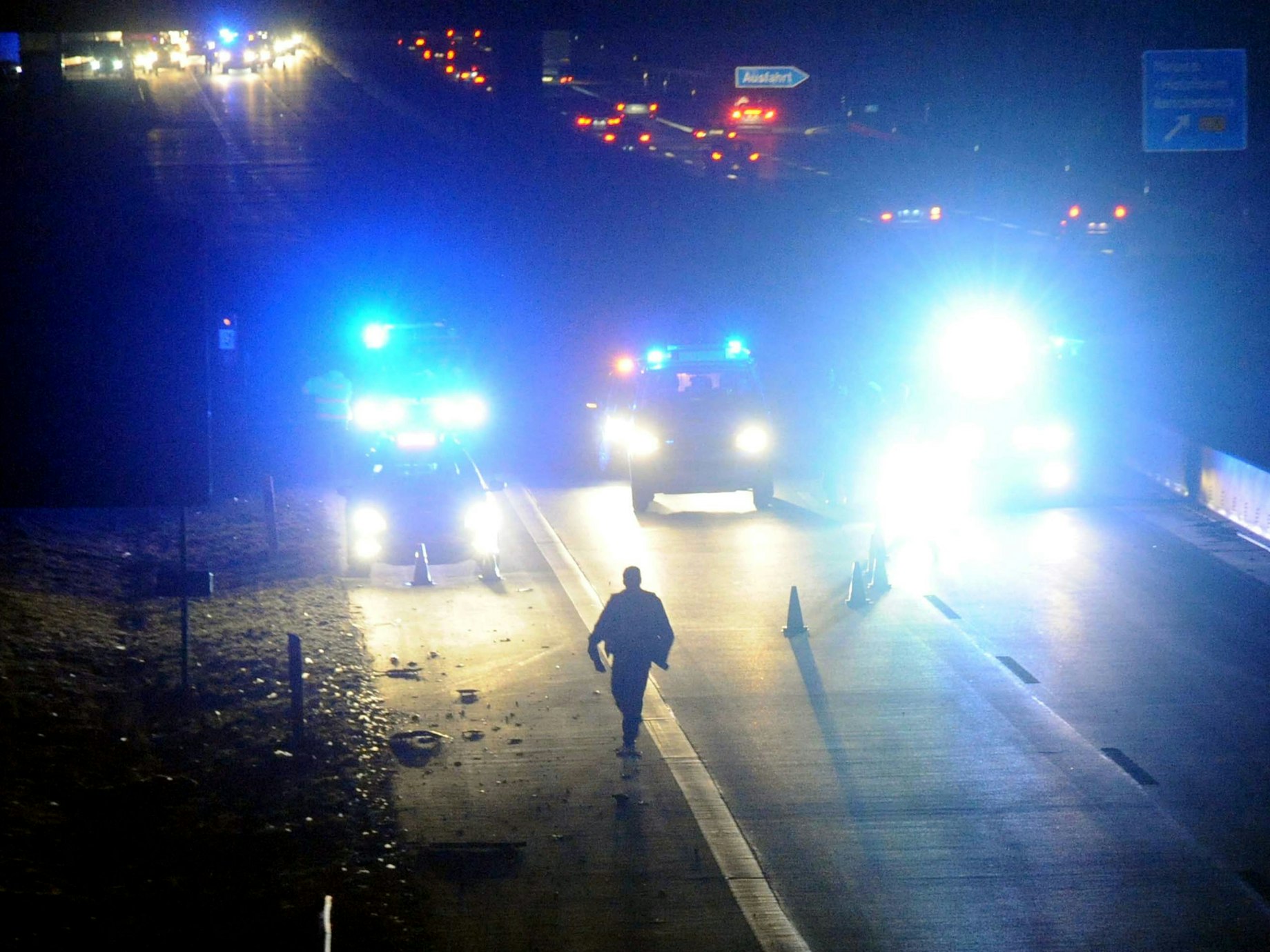 Polizeibeamte sperren eine Autobahn mit Warnhütchen.