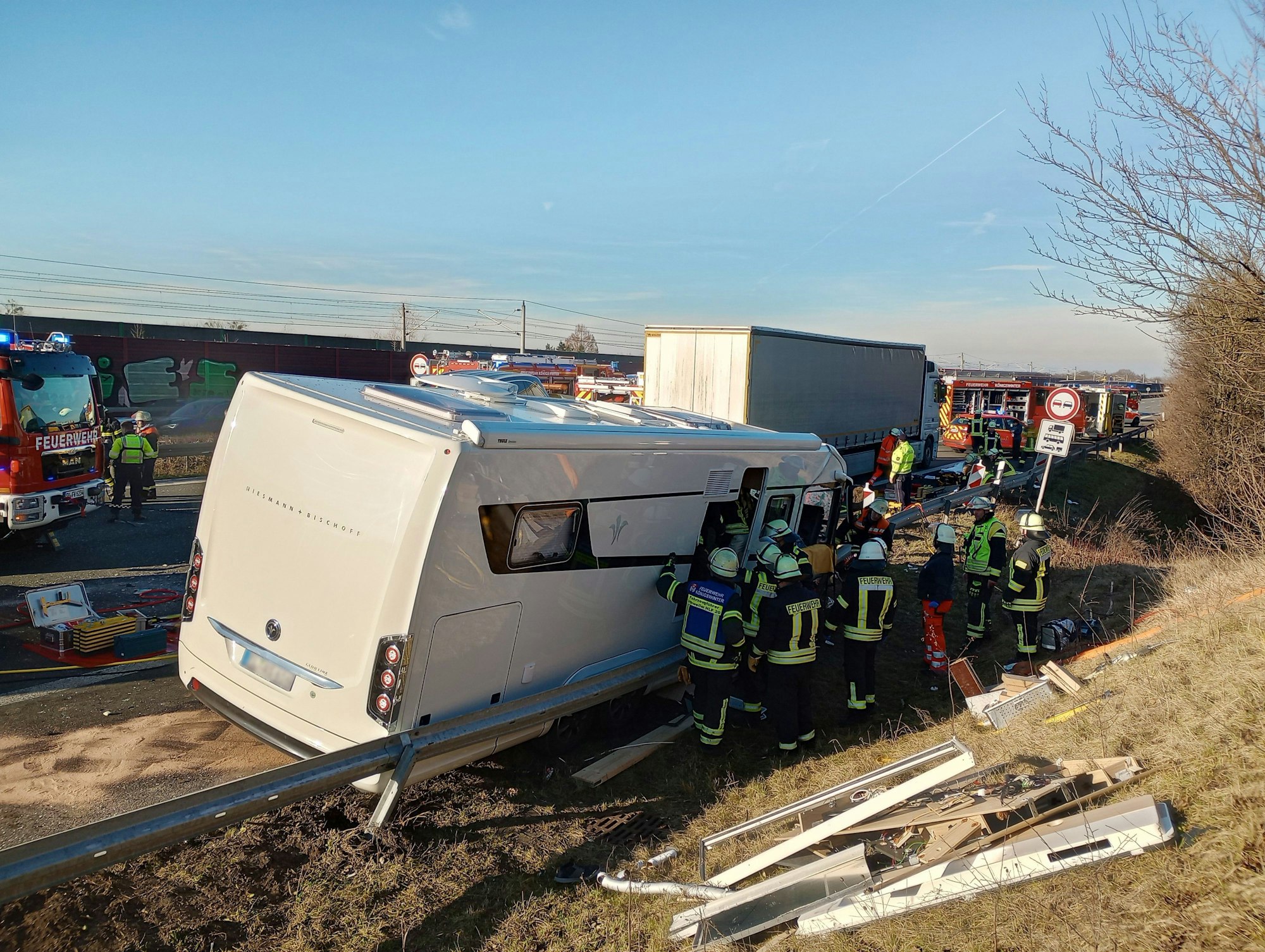 Ein Wohnmobil ist in eine Leitplanke geschleudert, mehrere Einsatzkräfte stehen an der geöffneten Tür.