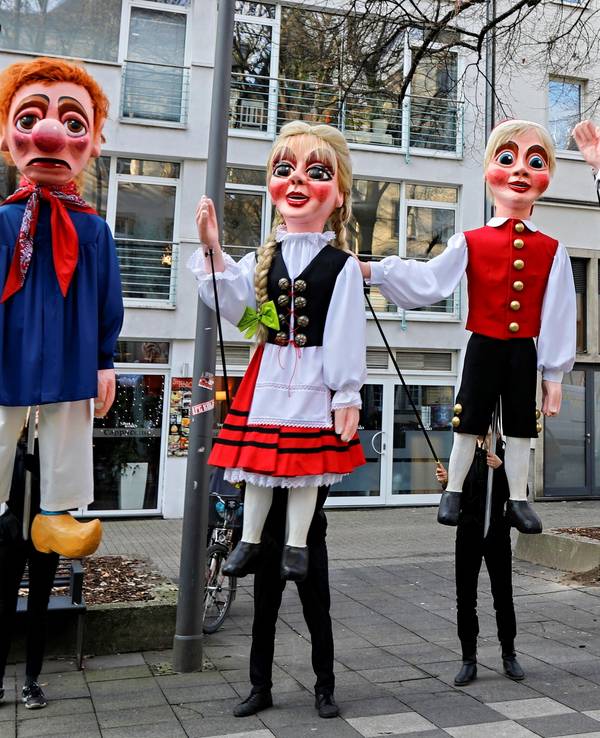 Vier Puppen stehen nebeneinander auf einer Straße.