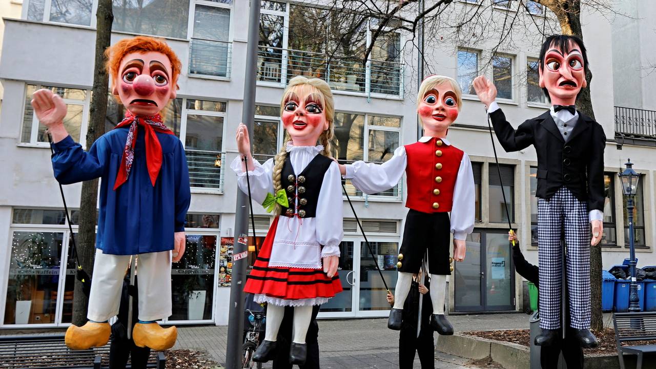 Vier Puppen stehen nebeneinander auf einer Straße.