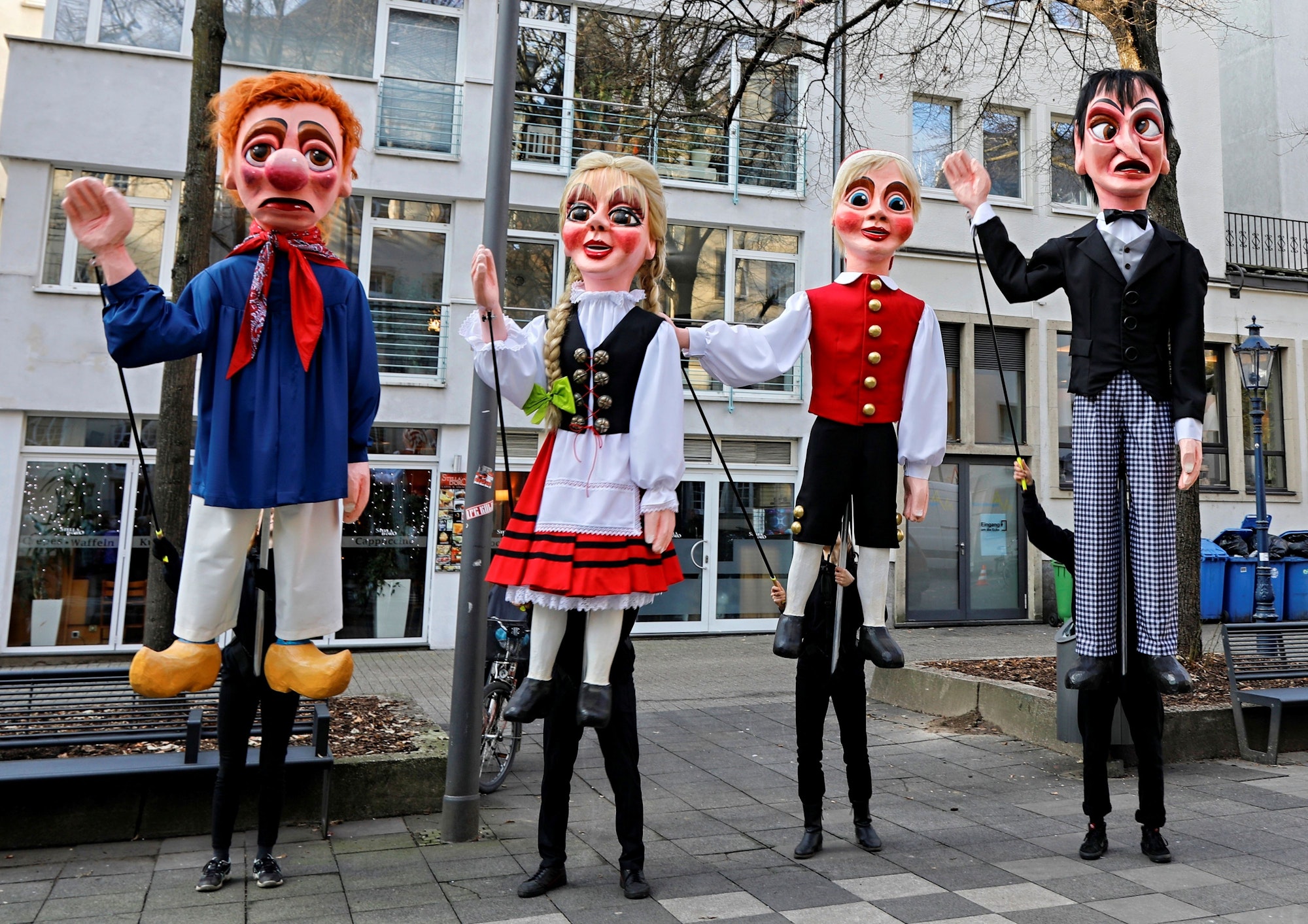 Vier Puppen stehen nebeneinander auf einer Straße.