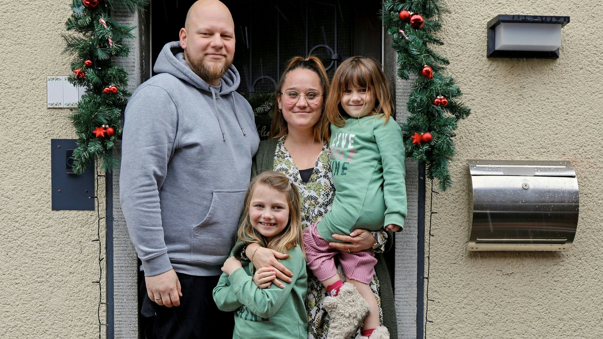 Die Familie steht vor ihrem Haus.