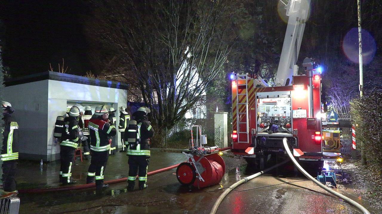 Feuerwehrleute stehen mit ihrem Fahrzeug vor einem Haus.