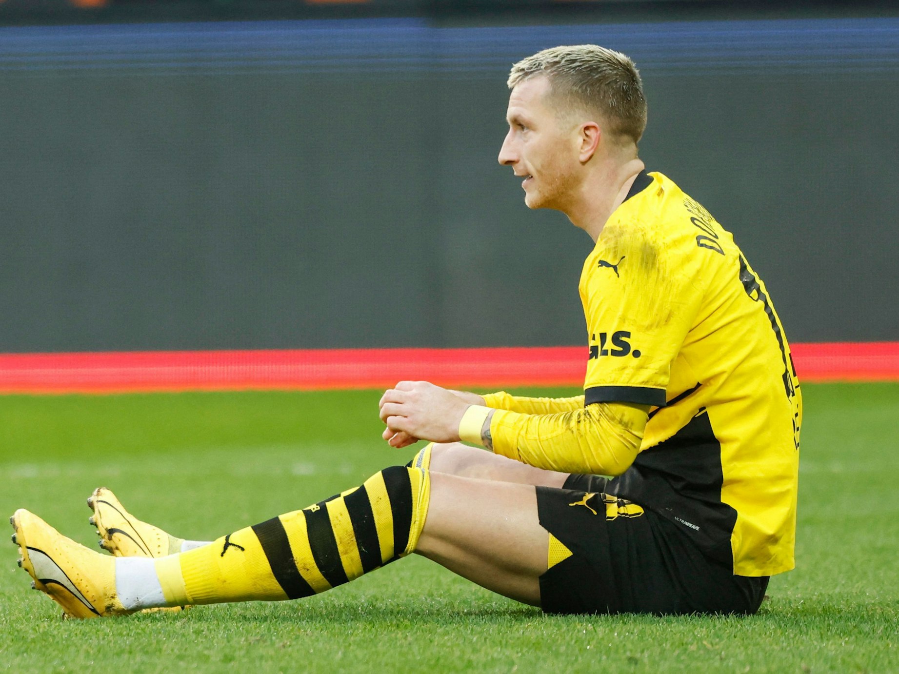 Marco Reus sitzt auf dem Rasen.