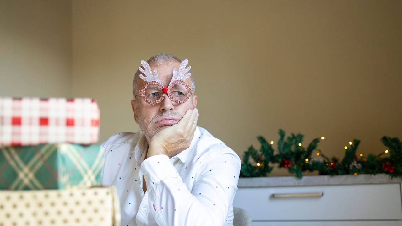 Upset aged man with grey hairs sitting near Christmas presents