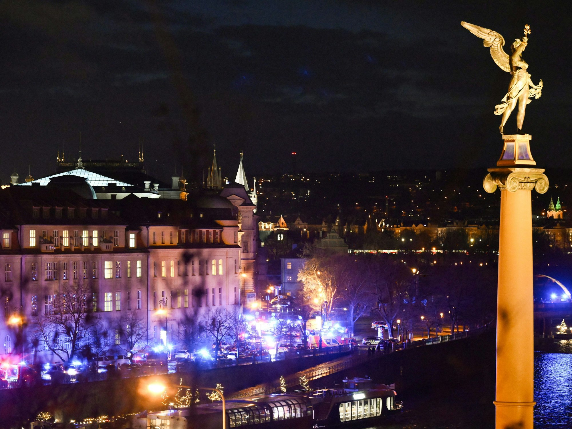 Feuerwehrfahrzeuge und Krankenwagen stehen am Ufer vor der Karls-Universität. An einer Hochschule in der Prager Innenstadt sollen Schüsse gefallen sein.