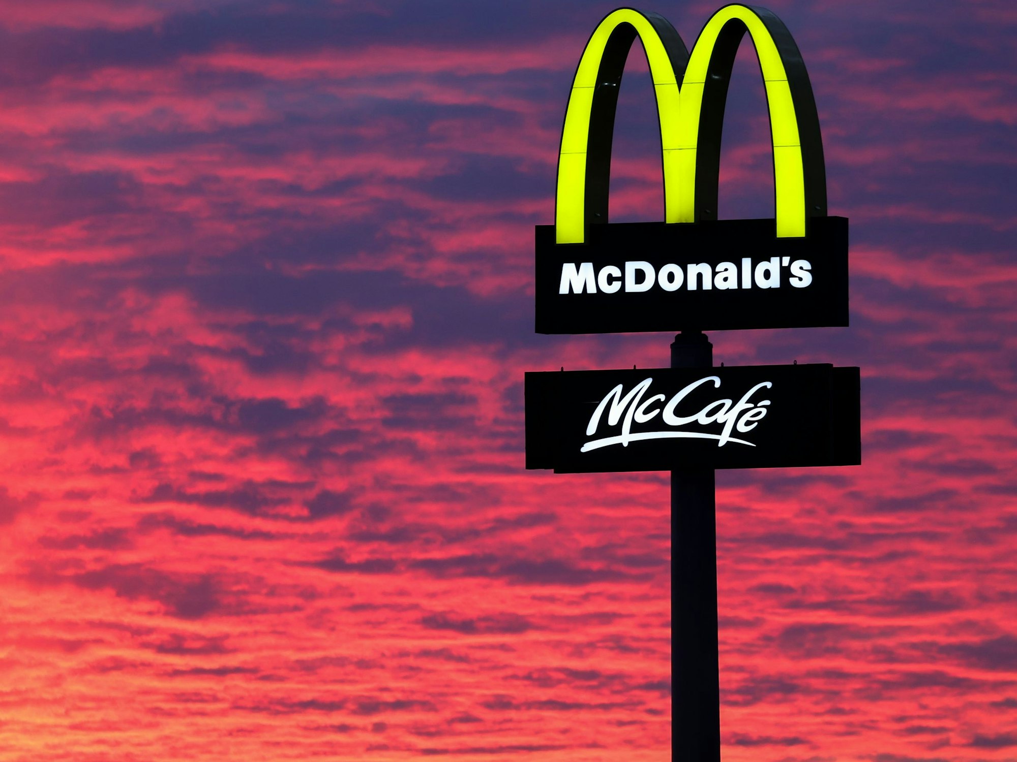 Der Abendhimmel leuchtet hinter einem McDonald's-Logo. McDonald's gibt am 25.04.2023 Zahlen für das 1. Quartal bekannt. +++ dpa-Bildfunk +++