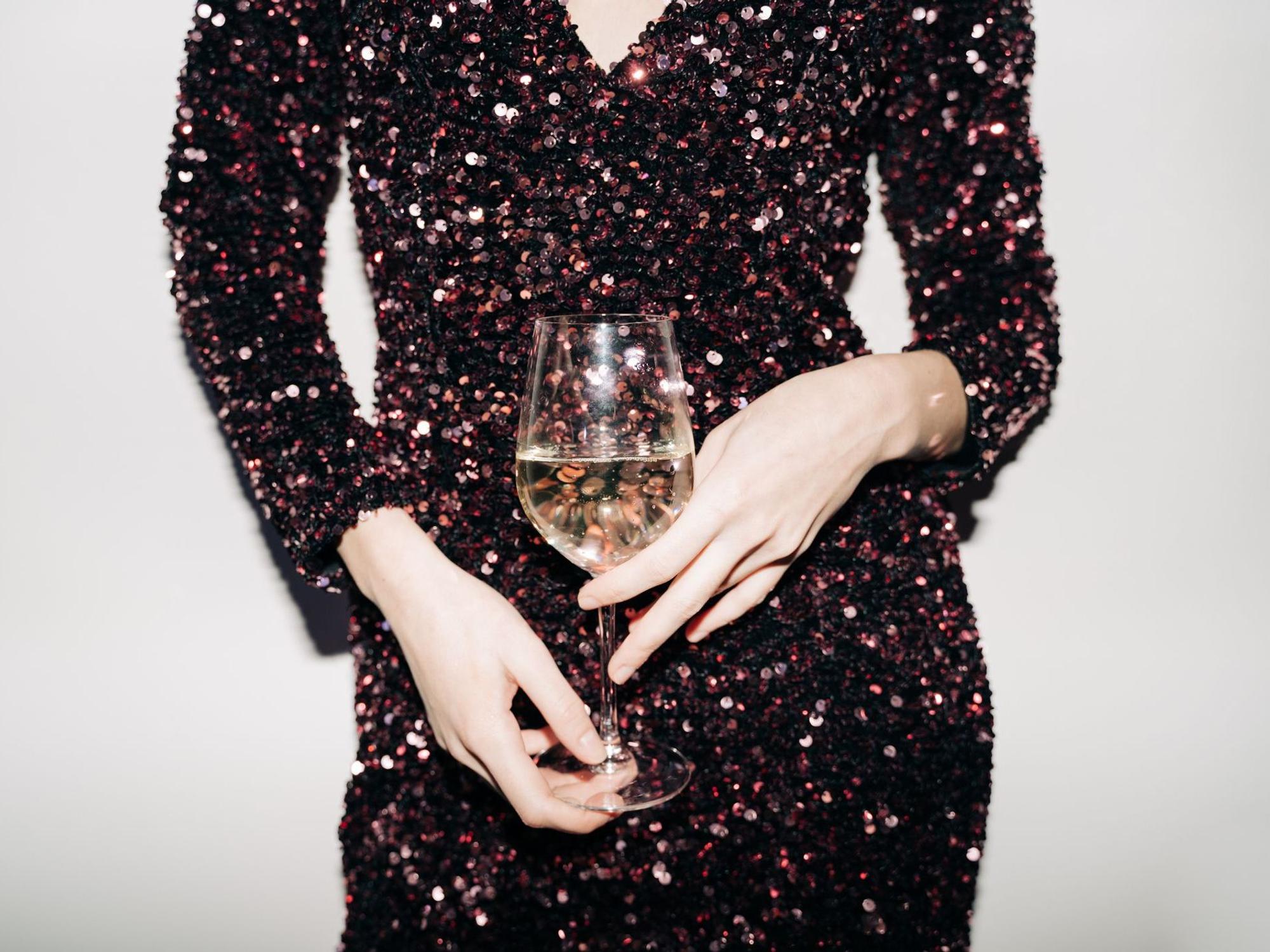 Eine Frau mit Paillettenkleid und Glas in der Hand