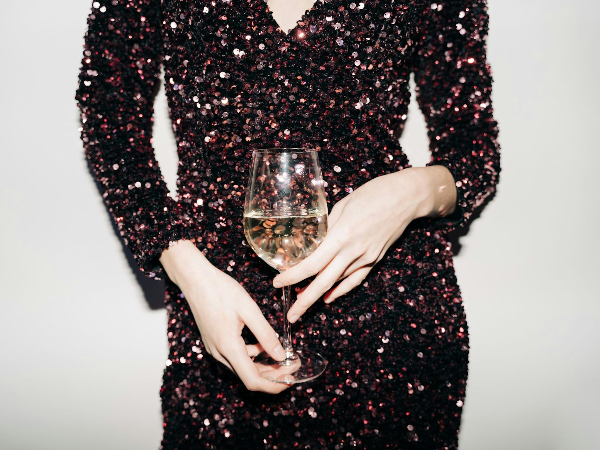 Eine Frau mit Paillettenkleid und Glas in der Hand