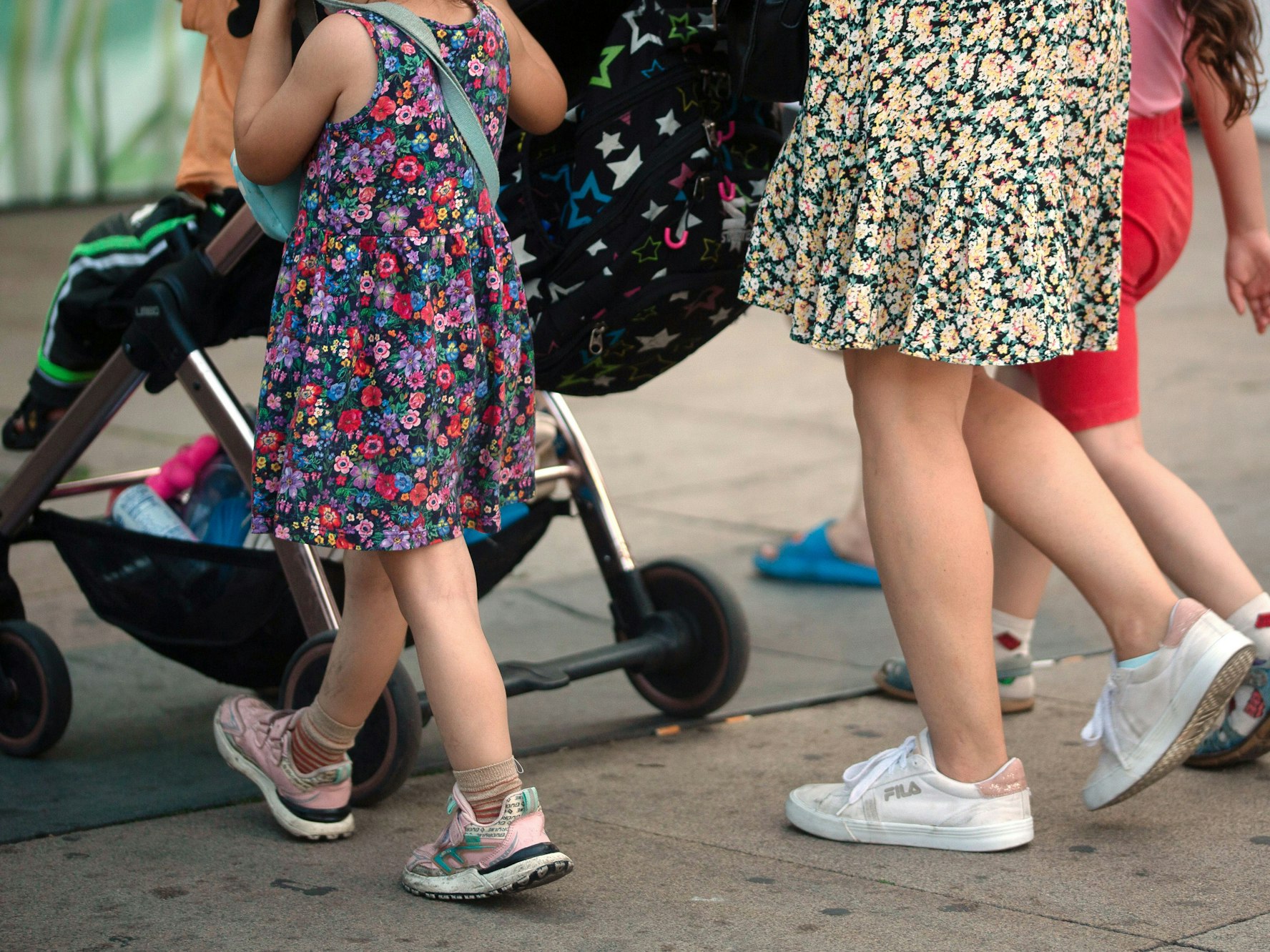 Eine Frau schiebt einen Kinderwagen und geht begleitet von mehreren Kindern, hier im Juli 2023 in Berlin.
