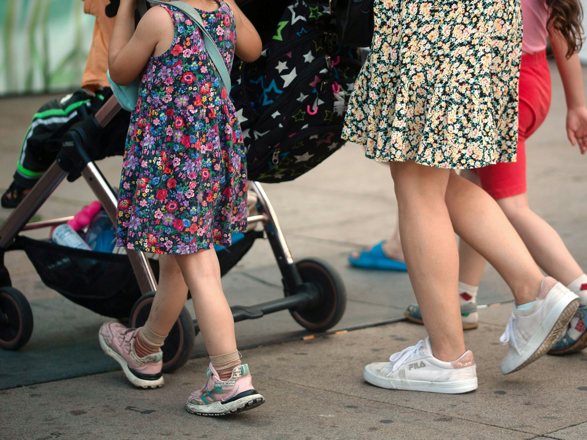 Eine Frau schiebt einen Kinderwagen und geht begleitet von mehreren Kindern, hier im Juli 2023 in Berlin.